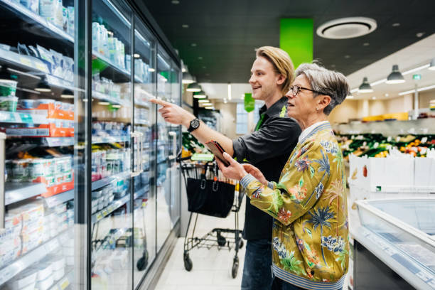 Un auxiliaire de vie aide une femme âgée à faire ses course dans son supermarché local.